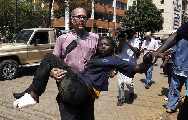 A journalist rescues a woman who was injured in a shootout between armed men and the police. (Photo by Thomas Mukoya/Reuters)