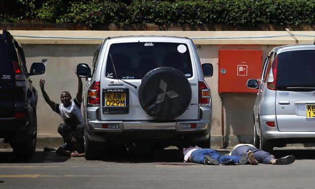 People come out from hiding under a car next to bodies in the mall's parking lot. (Photo by Goran Tomasevic/Reuters) 